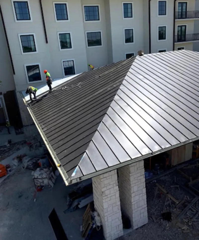 Crew installing standing seam metal roof panels on a commercial project in Royal Oak